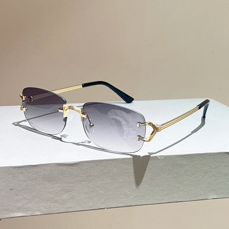 Gold-framed sunglasses with gradient lenses on a reflective surface